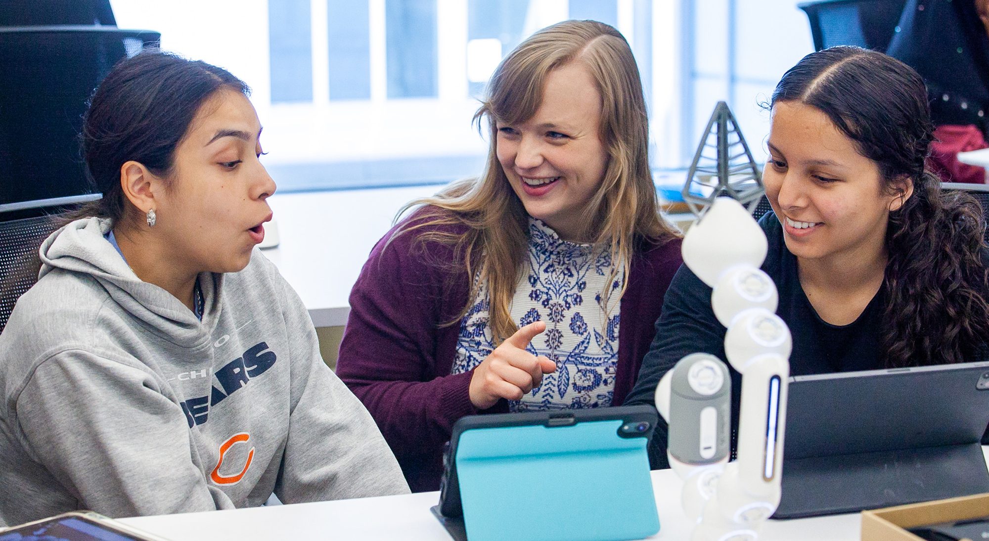 Two students interact with an instructor during a class