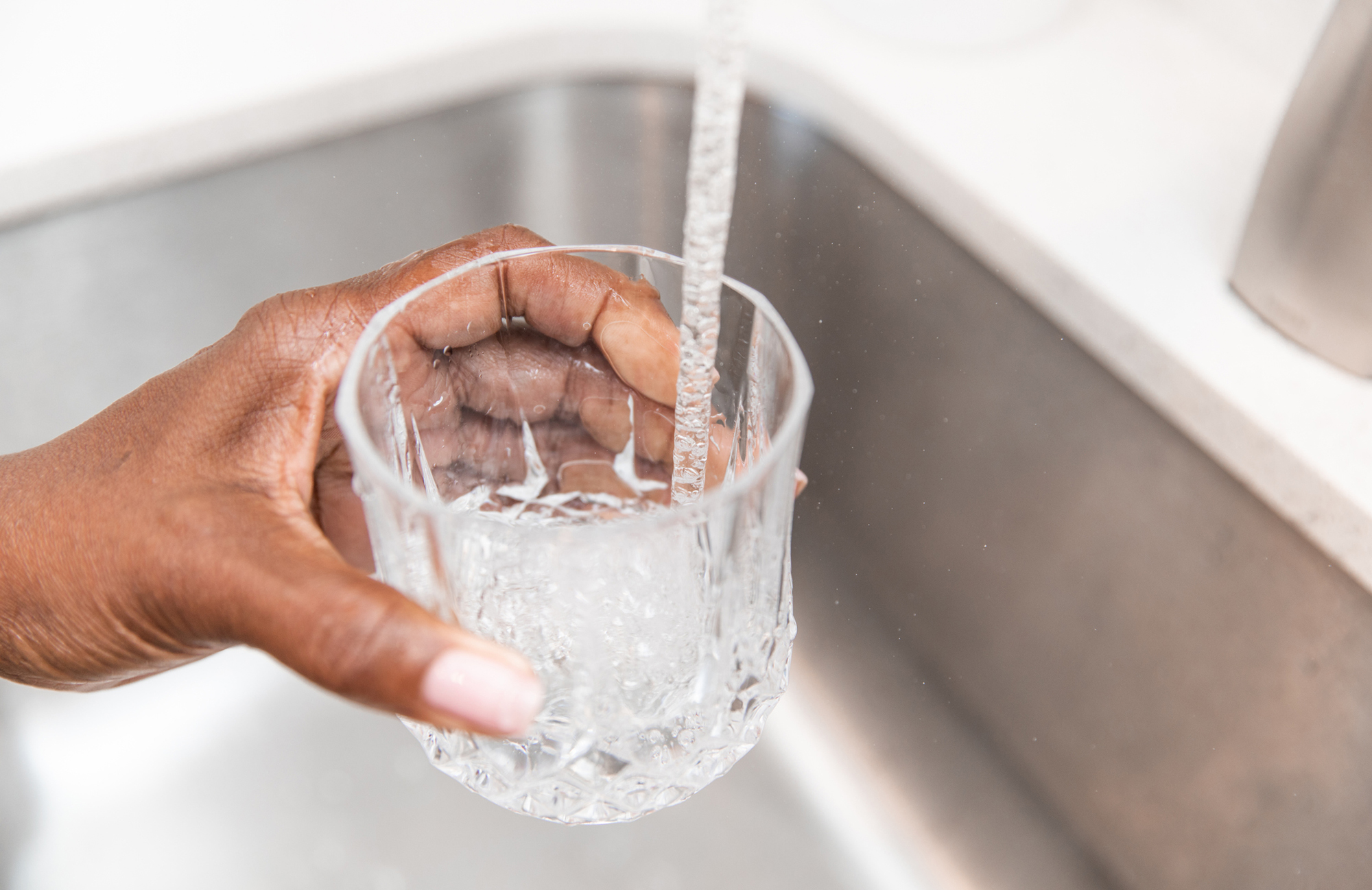 a glass being filled from a kitchen faucet