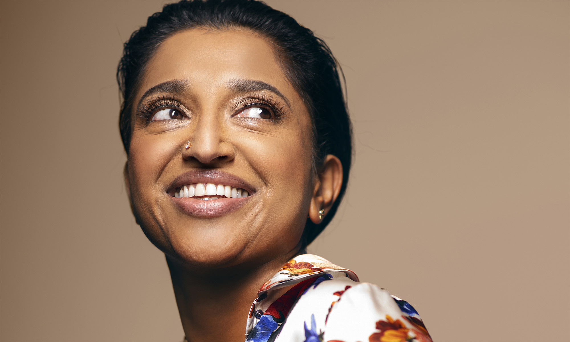 close of Sindhu Vee smiling and looking to the right, wearing a colorful blouse