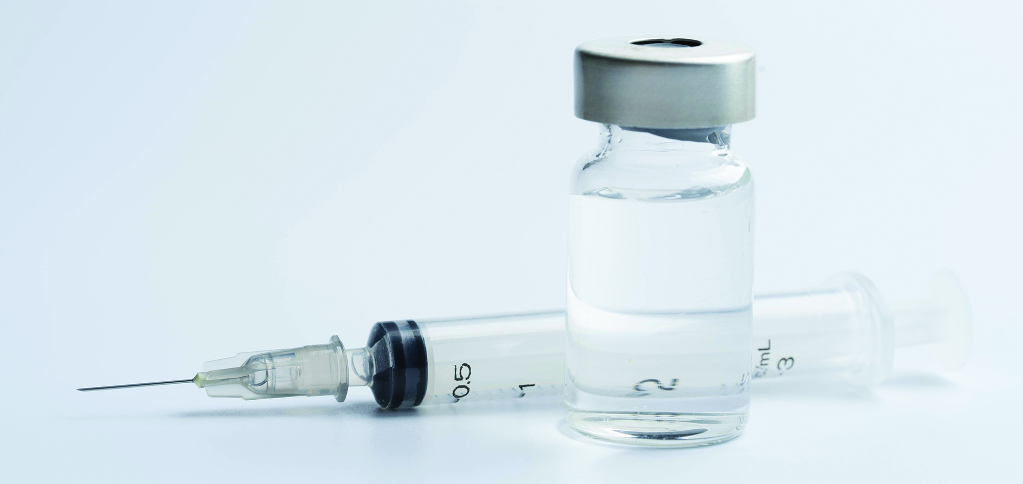 syringe lying next to a vial with clear liquid