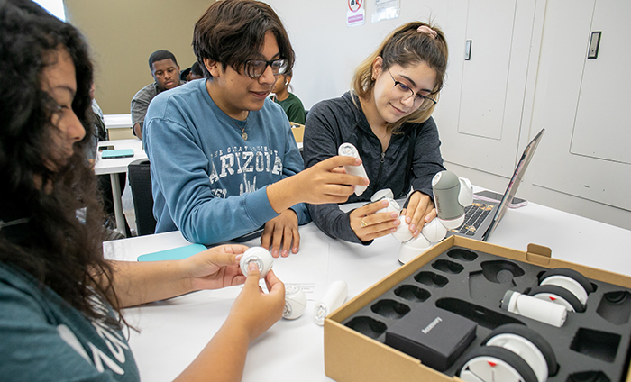 Three students at a table assembling a ClickBot