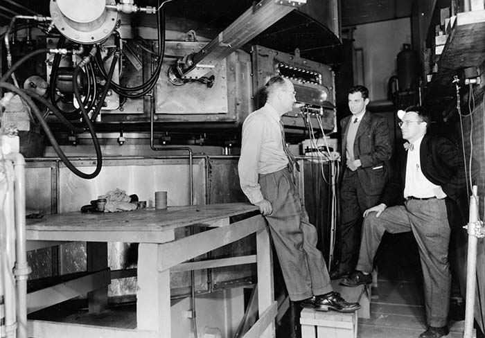 Enrico Fermi (left) chats with Herbert L. Anderson and John Marshall in front of the 170-inch, 450-MeV synchrocyclotron they designed