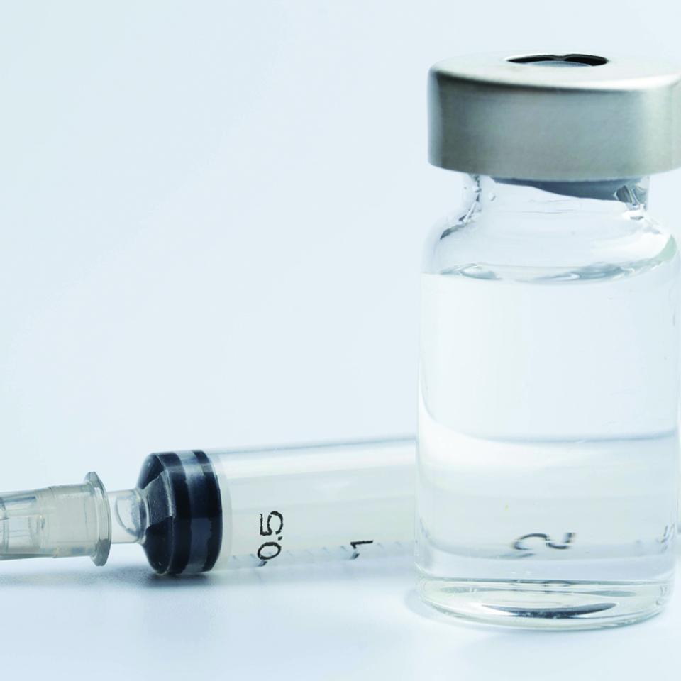 syringe lying next to a vial with clear liquid