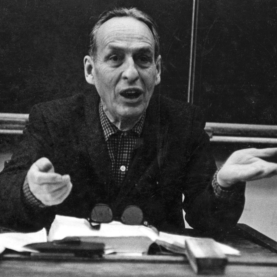 Norman Maclean sitting at a desk in classroom teaching