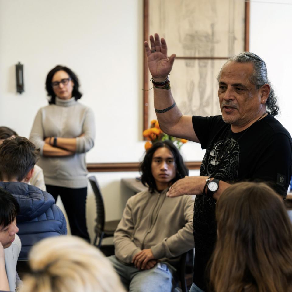 At a meeting of El Cafecito, Pilsen-based artist Ramón Marino explains, in Spanish, how to make traditional Day of the Dead crafts.